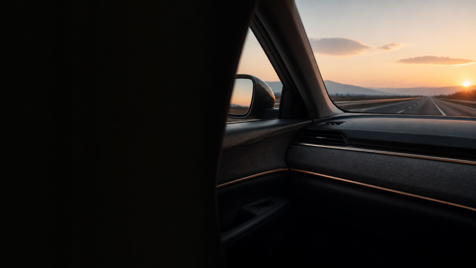The open road ahead, seen through a car window at sunset